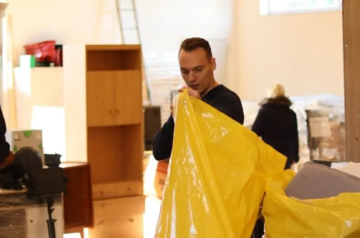 umzugshelfer bereitet verpackungsmaterial mit gelber schutzfolie vor